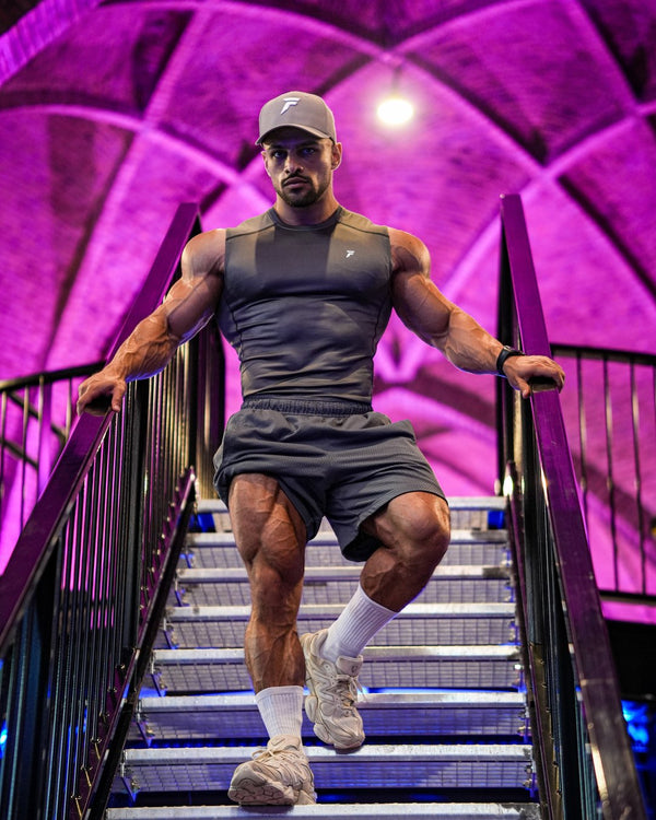 Atleet in grijze Frontline tanktop op een paars verlichte trap