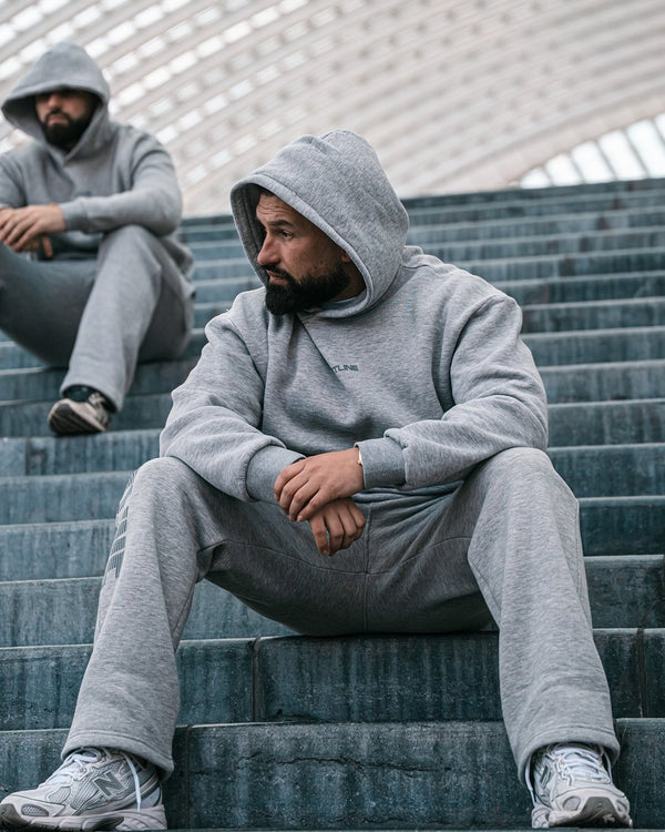 Twee mannen in grijze Frontline hoodies op een stadiontrap