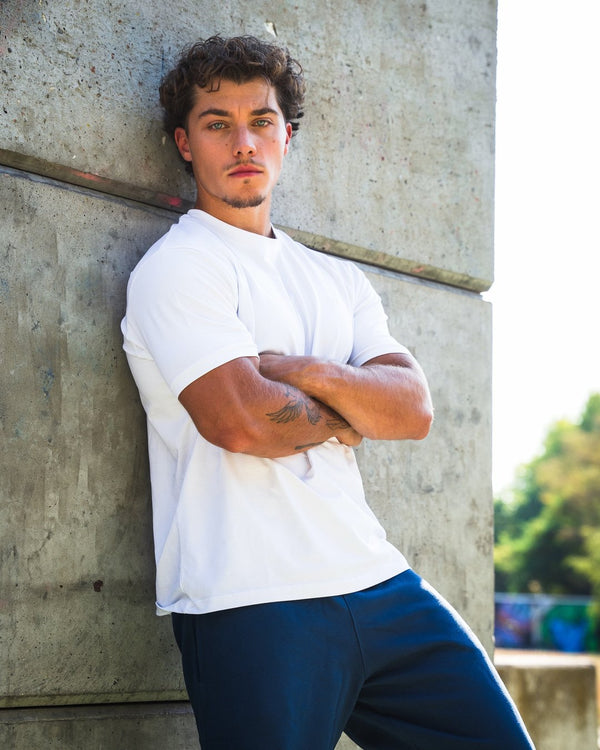 Man in wit Frontline T-shirt tegen een betonnen wand