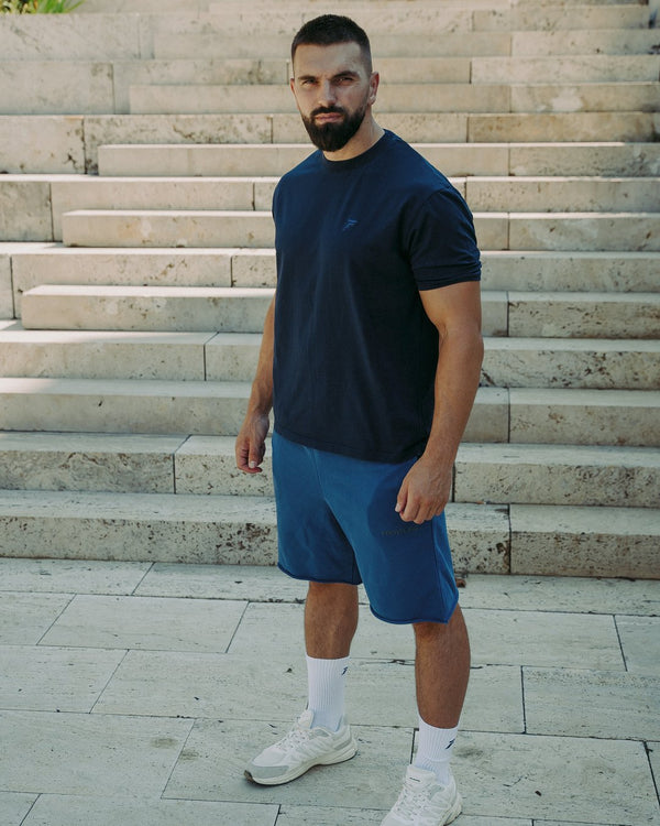 Man in navy Frontline T-shirt op een stenen trap